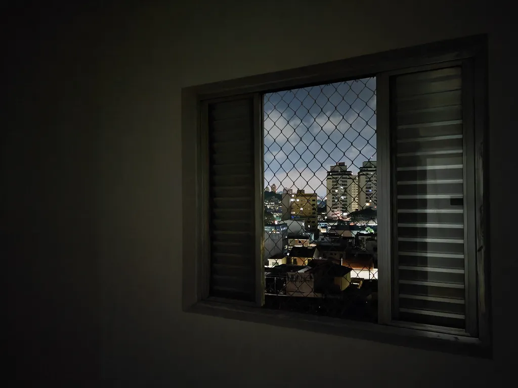 Foto no quarto com as luzes apagadas e com paisagem ao fundo. (Imagem: Maldditu Xavier/Canaltech)