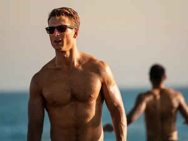 Glen Powell sem camisa em cena de Top Gun: Maverick