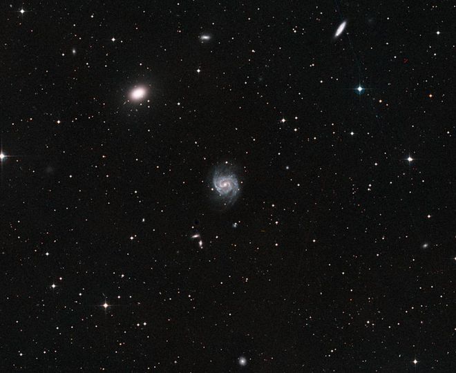 A galáxia NGC 1052 (canto superior esquerdo) e a galáxia próxima NGC 1042 (centro). Embora pareçam próximas, elas estão na verdade separadas por cerca de 20 milhões de anos-luz (Imagem: Reprodução/ESA/Hubble/NASA)