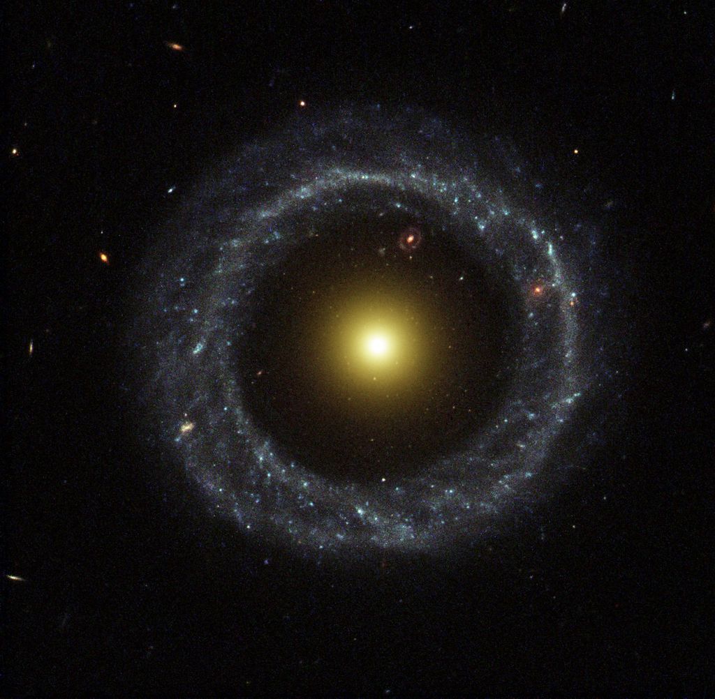 O objeto de Hoag: galáxia em anel com outra, que aprece uma única estrela gigantesca laranja; uma terceira galáxia parece estar dentro do anel, mas fica bem distante (Foto: NASA)