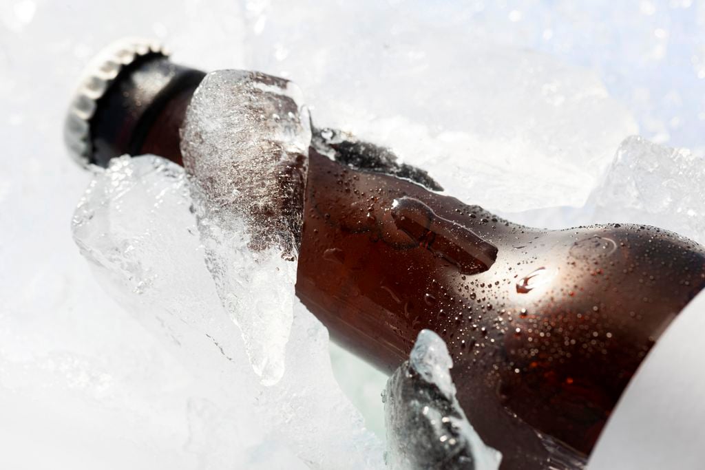 Close up de uma garrafa de cerveja com gelo em cima