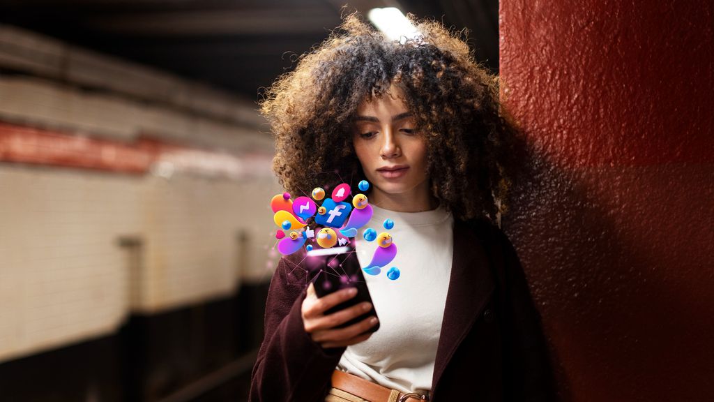 Mulher negraolha as notificações do celular enquanto está parada em uma estação de trem