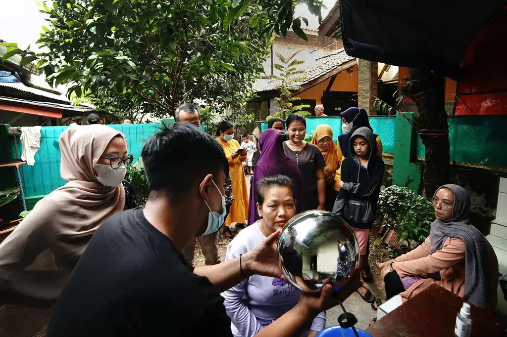 Funcionário da Worldcoin mostra o funcionamento do orbe a mulheres na Indonésia (Imagem: Reprodução/Worldcoin)