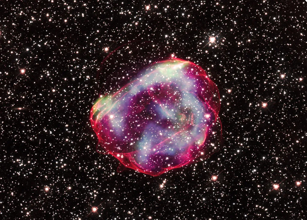 Imagem composta do remanescente de supernova; os dados de raios X de intensidade energética baixa, média e alta aparecem em verde, azul e roxo, respectivamente (Imagem: Reprodução/NASA/CXC/GSFC/B. J. Williams et al.; NASA/ESA/STScI)