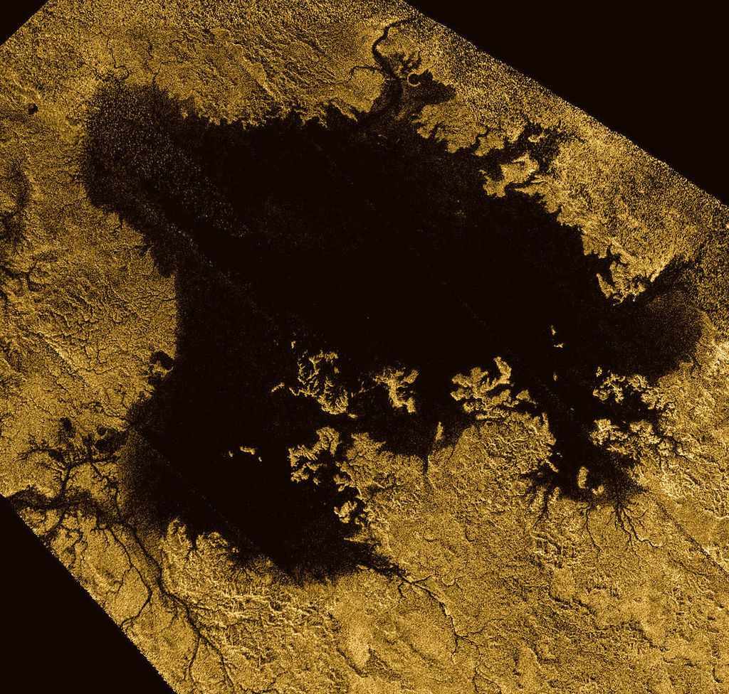 A região marcada na cor preta é um lago de metano, e a região na cor dourada é a superfície sólida composta por gelo (Imagem: NASA/JPL-Caltech/ASI/Cornell)