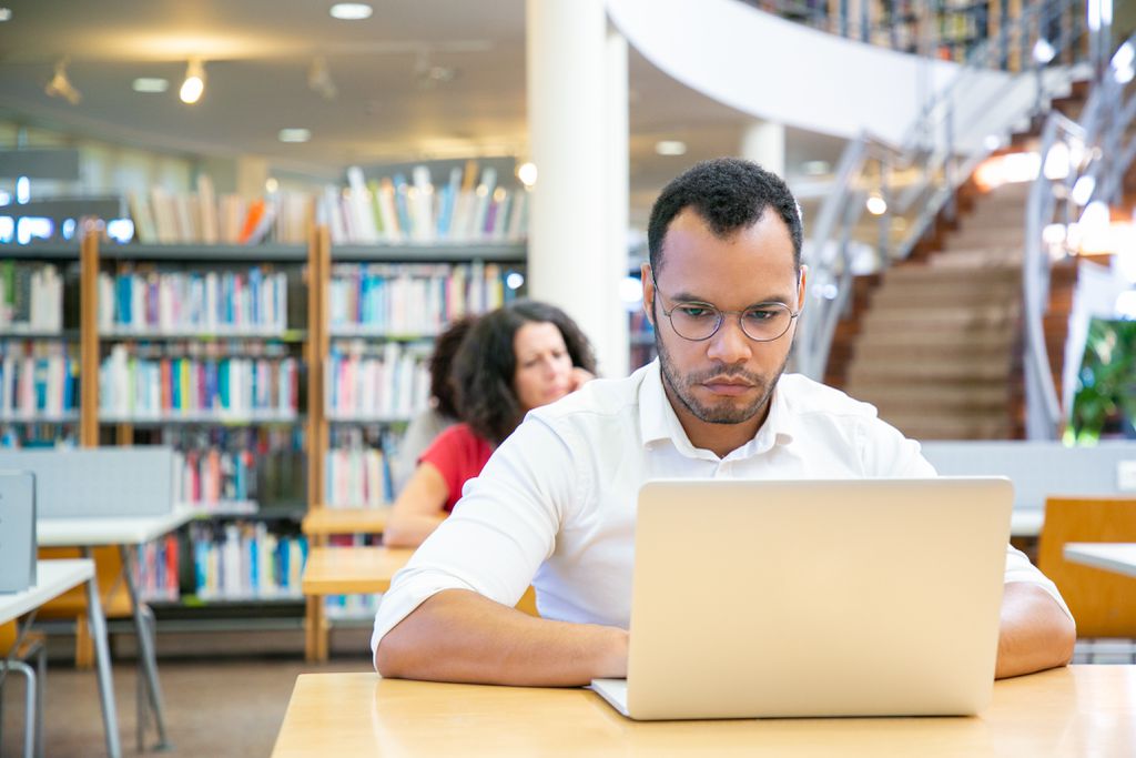 Estudante digita em um computador em uma biblioteca