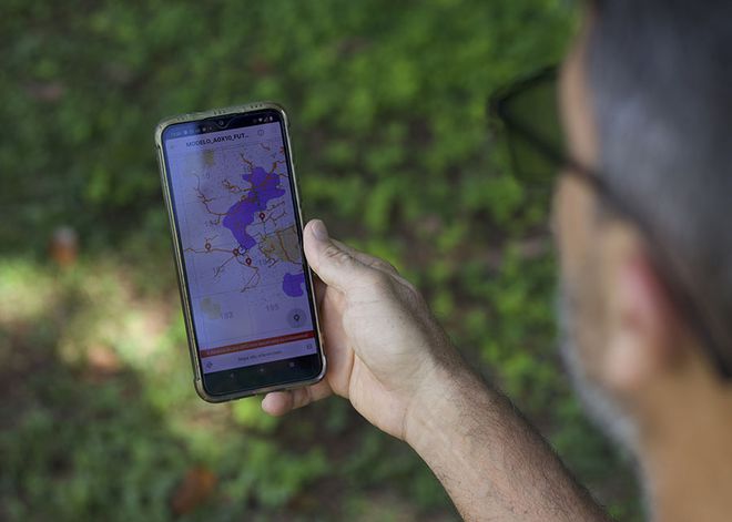Homem segurando um celular com mapa na tela
