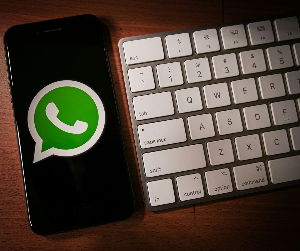Celular com o logo do WhatsApp ao lado de um teclado de PC