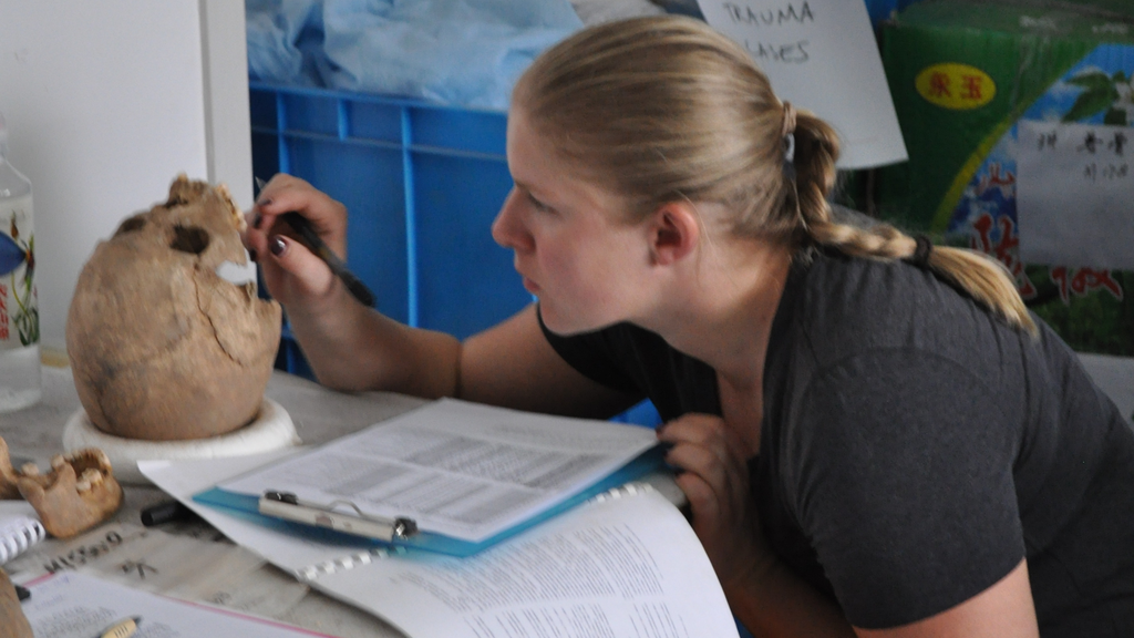A pesquisadora Jenna Dittmar enquanto estuda um dos crânios encontrados no cemitério da Idade do Bronze, na China (Imagem: Elizabeth Berger)