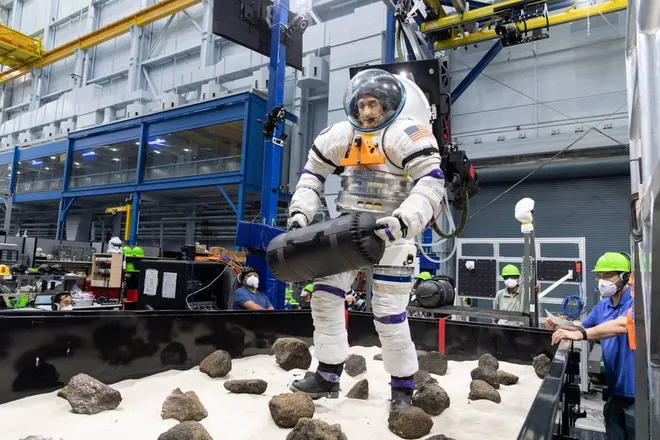 O astronauta voluntário carrega um objeto por um caminho cheio de obstáculos enquanto veste um traje espacial pressurizado (Imagem: Reprodução/NASA)