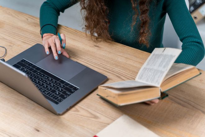 Pessoa com computador e livro na mão