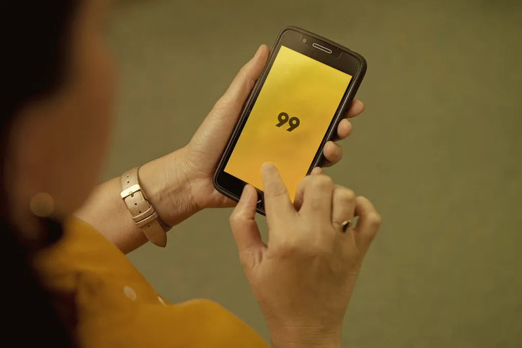 Mulher segurando um celular com o aplicativo da 99 aberto