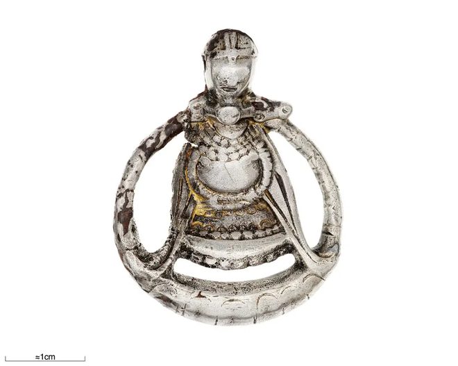 Este pingente, encontrado na Suécia e feito no século X, mostra uma mulher segurando sua barriga grávida enquanto usa um capacete de guerra — as mulheres vikings podiam ser combatentes durante a gravidez (Imagem: Myrin, Ola, Historiska museet/SHM/CC BY 4.0)
