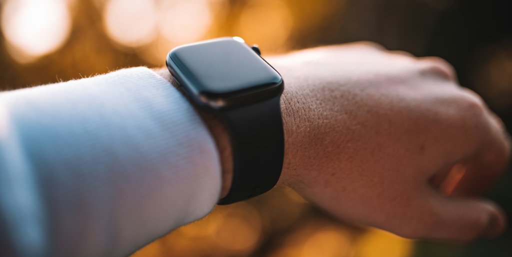 Pessoa usando um smartwatch com GPS em um pulso, exibindo informações de corrida, com paisagem urbana ao fundo.