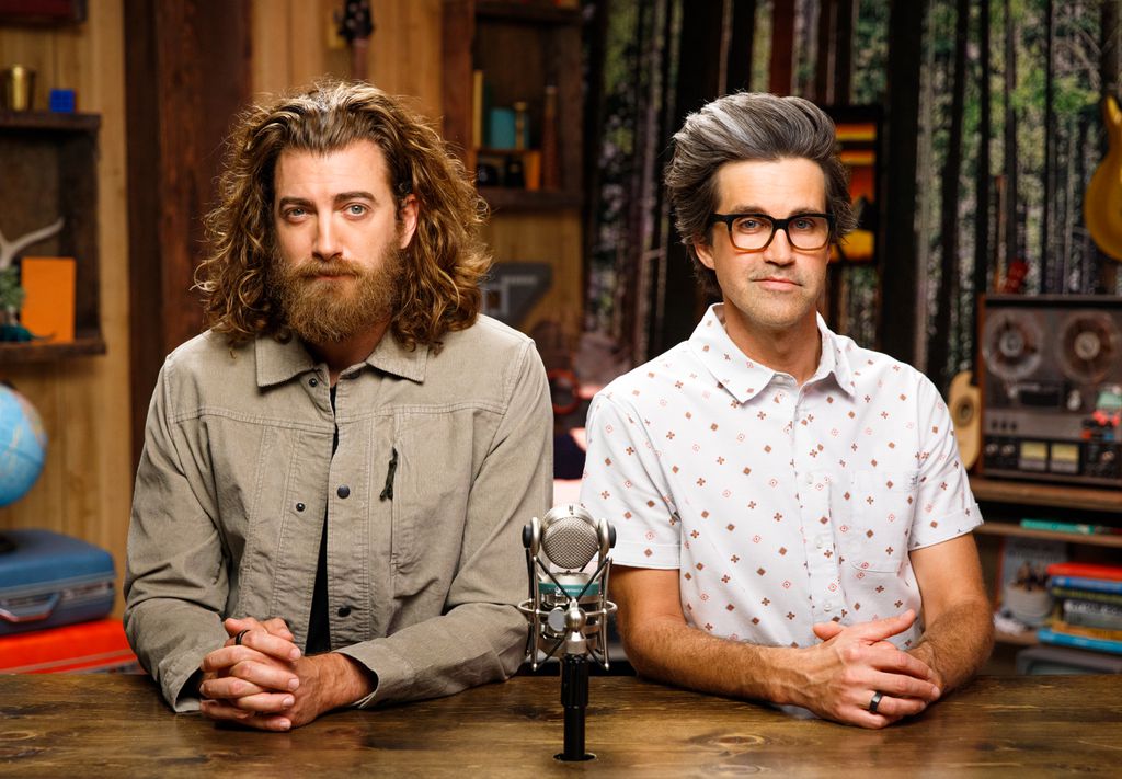 Foto da dupla Rhett e Link em frente a um microfone para gravação de um podcast