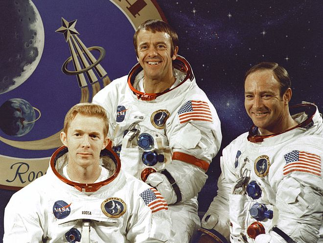 Stuart A. Roosa, Alan B. Shepard Jr. e Edgar D. Mitchell, com o emblema da missão ao fundo (Imagem: Reprodução/NASA)