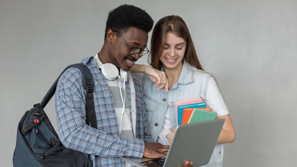 Dois estudantes em pé mexendo em um notebook