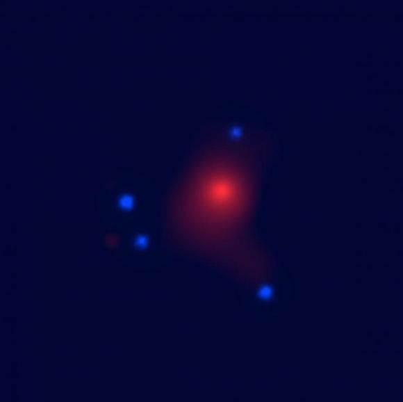 Imagem de raios-X do sistema SDSS J1004 + 4112, obtida pelo Observatório de Raios-X Chandra da NASA; o ponto central vermelho é a emissão do gás quente no aglomerado de galáxias primeiro plano e os pontos azul são as imagens formadas a partir do quasar no fundo. Os objetos de massa planetária foram detectados no aglomerado de galáxias, que tem uma idade de cerca de metade do Universo (Imagem: Universidade de Oklahoma)