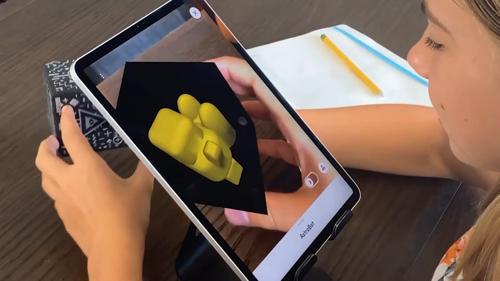 Criança usa o cubo Merge com um tablet para visualizar imagens em 3D