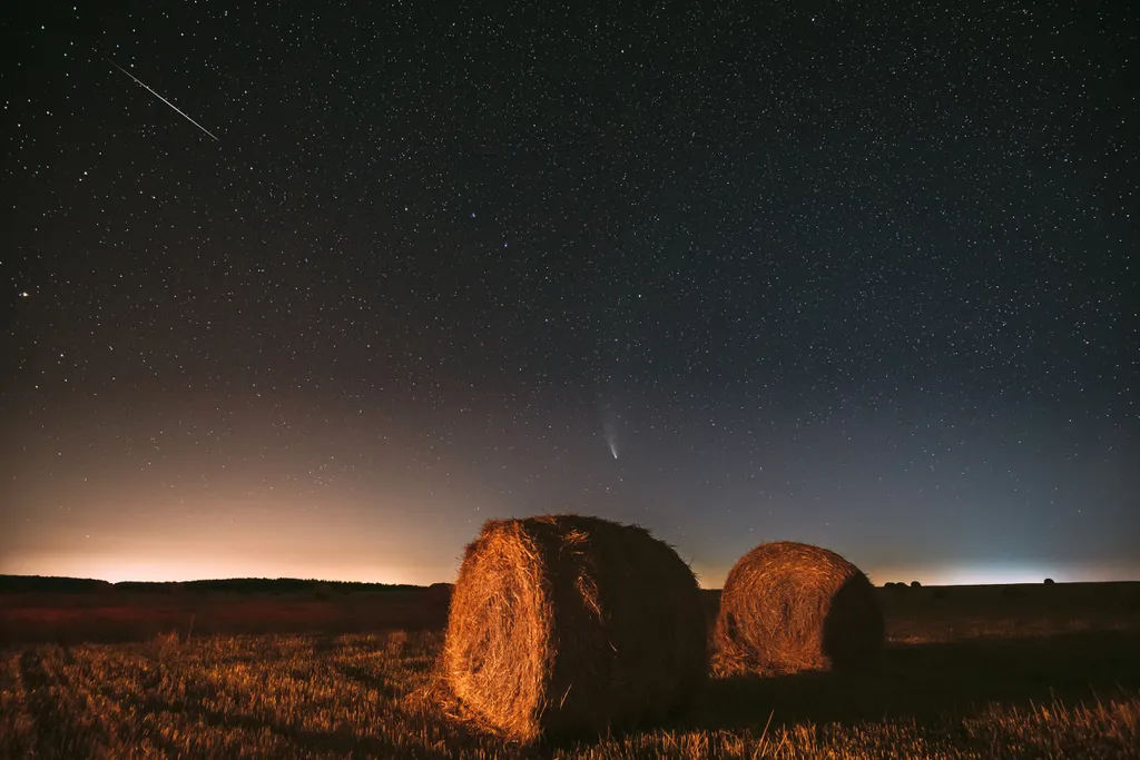 Um meteoro risca o céu no canto superior esquerdo, com um cometa aparecendo na parte central da foto (Imagem: Grigory_bruev/Envato)