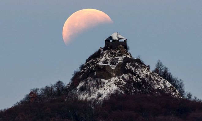 A lua durante o eclipse acima de um castelo na Hungria (Foto: Peter Komka/EPA)