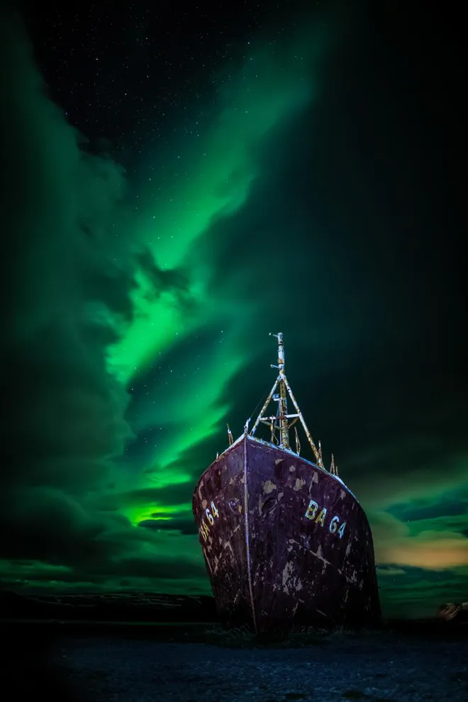 A aurora boreal atrás do navio Gardur, Islândia (Imagem: Reprodução/Carl Gallagher)