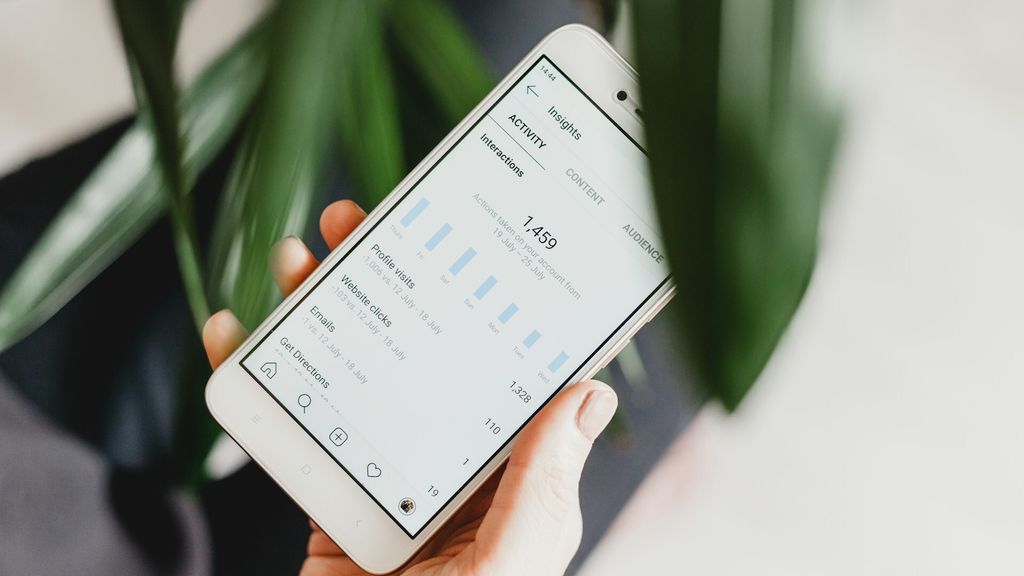 Mão segurando um smartphone branco com a tela de 