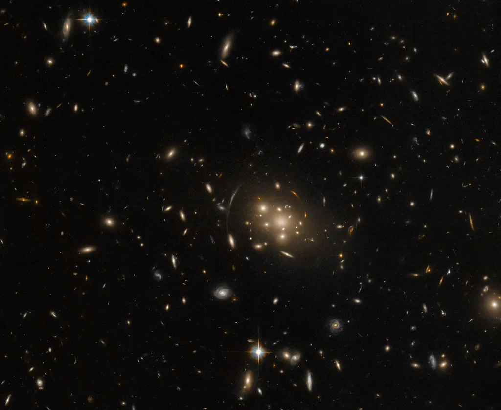 O aglomerado de galáxias SPT-CL J0019-2026 é tão massivo que causou uma lente gravitacional (Imagem: Reprodução/ESA/Hubble & NASA, H. Ebeling)