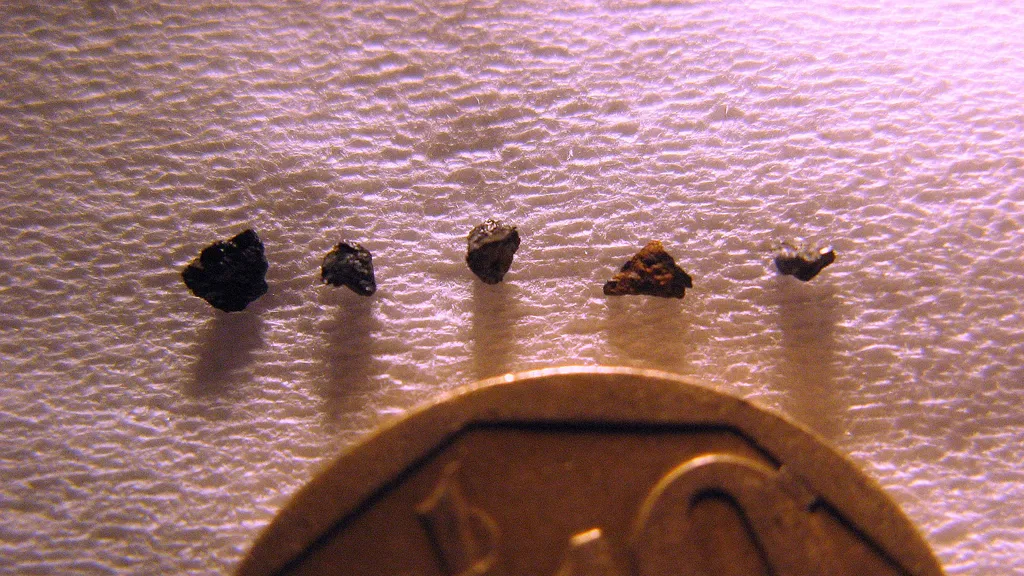 Tamanho das pequenas amostras da rocha Hypatia em comparação a uma moeda (Imagem: Reprodução/Jan Kramers)