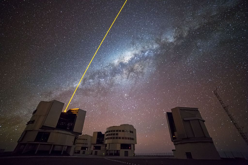  O feixe de laser amarelo é uma "estrela artificial" que faz parte do sistema de óptica adaptativa, usado para os astrônomos calibrarem as observações e, assim, não serem afetados pelos efeitos causados pela turbulência atmosférica (Imagem: Reprodução/ESO/G. Lombardi)