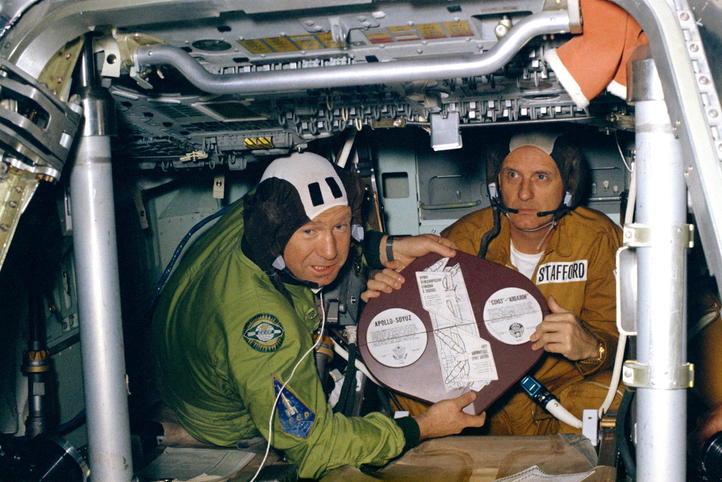 Cosmonauta Aleksei A. Leonov e Thomas Stafford, comandantes das suas respectivas tripulações, exibindo a placa comemorativa da Apollo-Soyuz (Imagem: Reprodução/NASA)