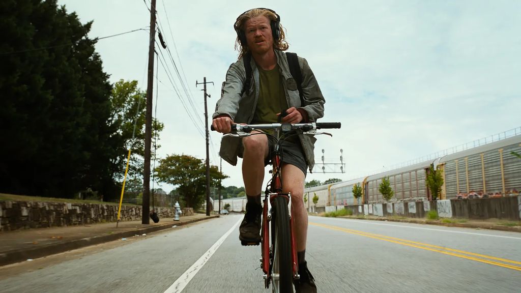 Cena do filme Bugonia com Jesse Plemons andando de bicicleta