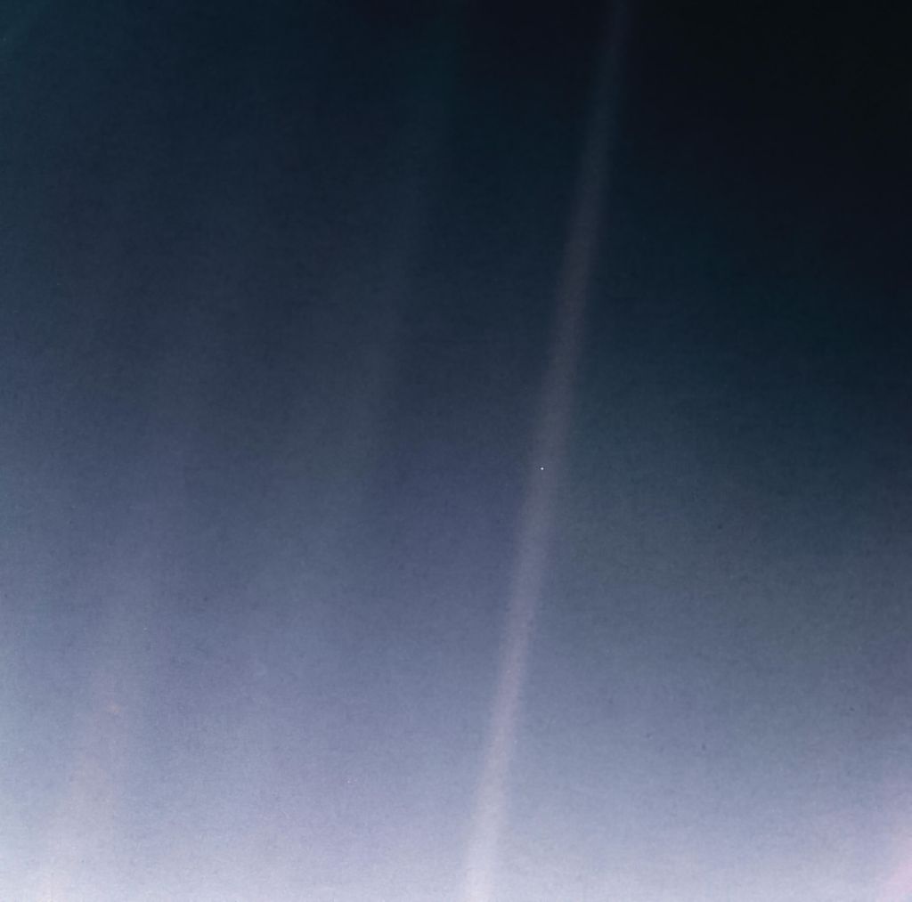 Terra, o pálido ponto azul que aparece sendo atingido por um raio de luz solar nesta icônica imagem que acaba de ser remasterizada (Foto: NASA)